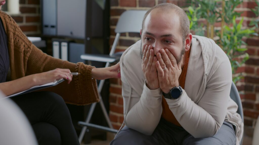 Close up of man dealing with anger management issues in front of people at aa group meeting