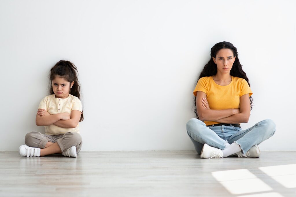 Grumpy Young Mother And Little Daughter Sitting Offended After Argue At Home