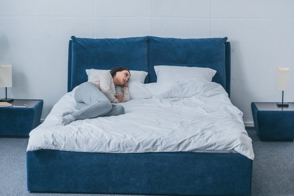 sad lonely woman in pajamas lying in bed at home